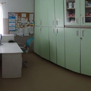 widok gabinetu doraźnej pomocy; na zdjęciu kozetka dla pacjenta, lodówka na leki, biurko pielęgniarskie z dwoma skomputeryzowanymi stanowiskami, szafa na leki i krzesło dla Mieszkańca, waga